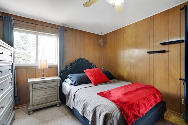 bedroom featuring ceiling fan, light carpet, and wood walls