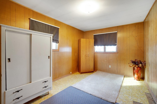 bedroom featuring tile patterned floors, a closet, baseboards, and wooden walls