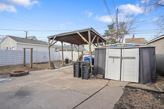 view of patio with a shed, an outdoor fire pit, an outdoor structure, and fence