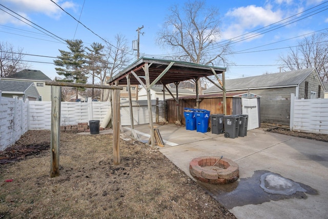 view of yard with a fenced backyard, a shed, a fire pit, an outdoor structure, and concrete driveway