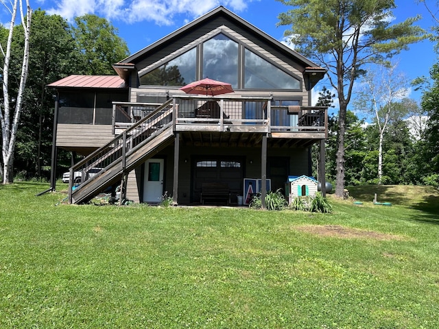 back of property featuring an attached garage, stairs, a deck, and a lawn