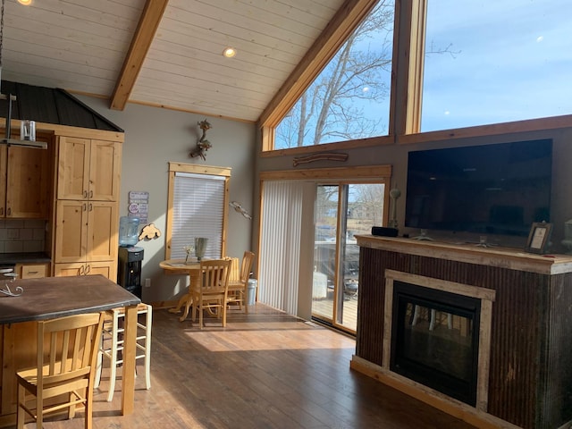 dining space with a glass covered fireplace, wood ceiling, vaulted ceiling with beams, and hardwood / wood-style floors