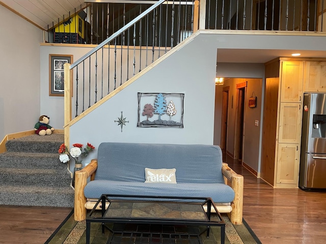 staircase featuring high vaulted ceiling, wood finished floors, and baseboards