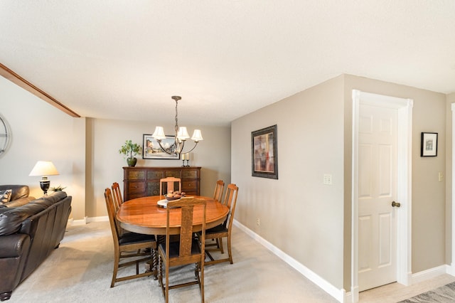 dining space featuring a notable chandelier, baseboards, and light carpet