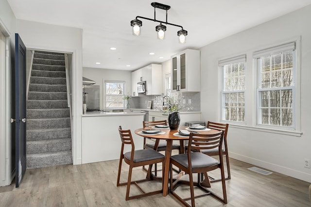 dining space featuring light wood finished floors, baseboards, visible vents, stairway, and recessed lighting