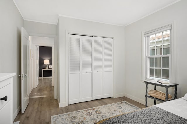 bedroom featuring ornamental molding, a closet, baseboards, and wood finished floors