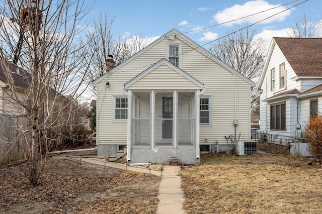 bungalow-style house with a sunroom, a chimney, and central AC