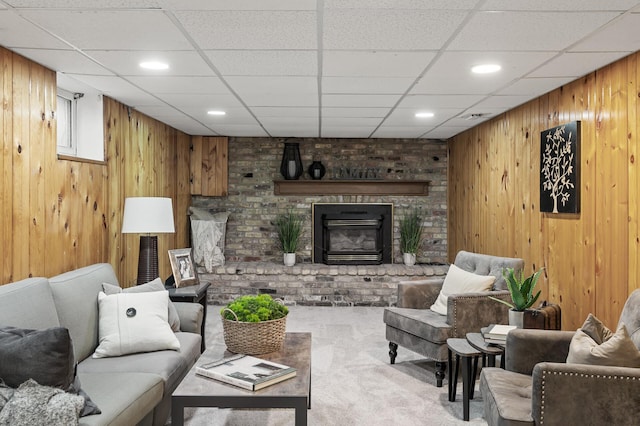 carpeted living area featuring wood walls, a brick fireplace, a paneled ceiling, and recessed lighting