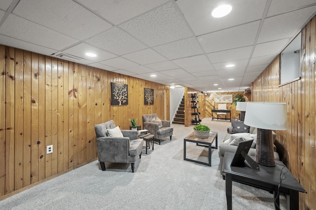 carpeted living room featuring wooden walls, recessed lighting, and stairway