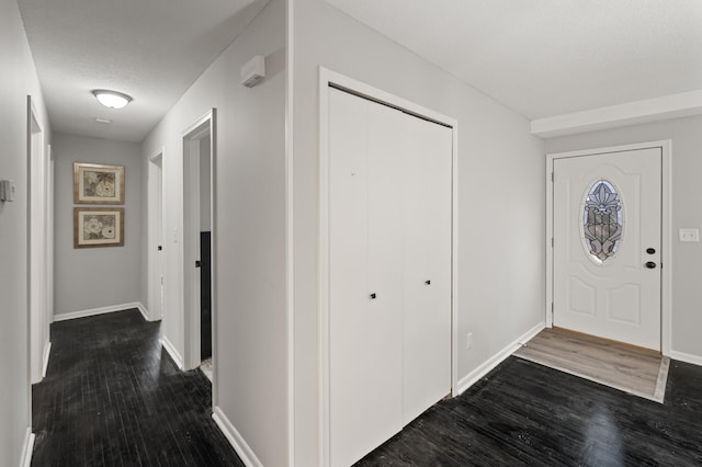 foyer entrance featuring a textured ceiling, baseboards, and wood finished floors