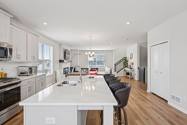 kitchen with a sink, light countertops, appliances with stainless steel finishes, a kitchen bar, and open floor plan