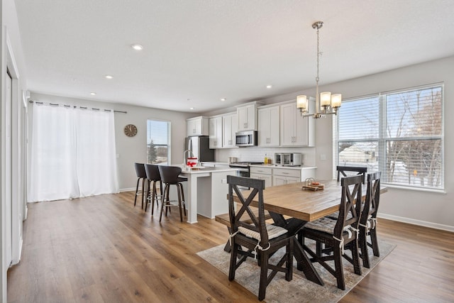 dining space featuring an inviting chandelier, recessed lighting, wood finished floors, and baseboards