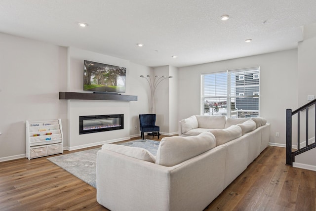 living room with recessed lighting, baseboards, wood finished floors, and a glass covered fireplace