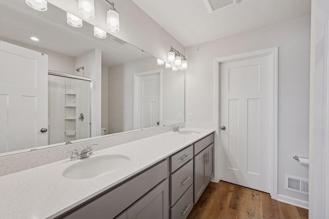 full bathroom with visible vents, wood finished floors, walk in shower, and a sink