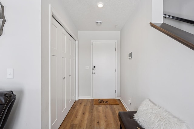 entryway featuring a textured ceiling, baseboards, and wood finished floors