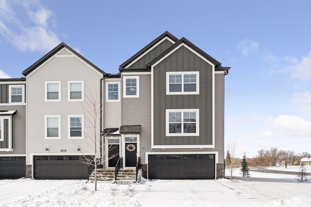 view of front of home with stone siding, board and batten siding, driveway, and a garage