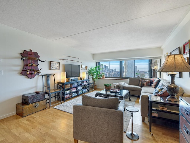 living room with light wood-style flooring, baseboards, and a textured ceiling