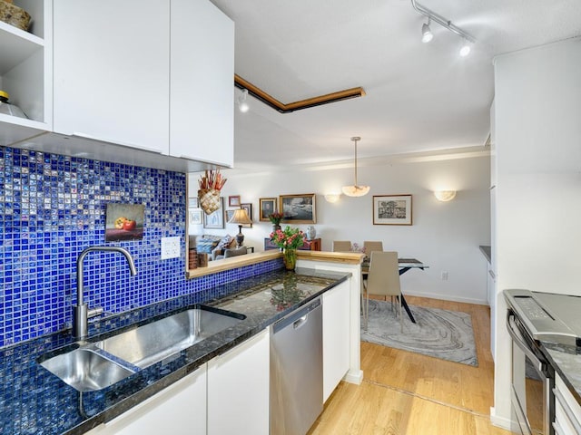 kitchen featuring backsplash, light wood-style flooring, appliances with stainless steel finishes, white cabinetry, and a sink