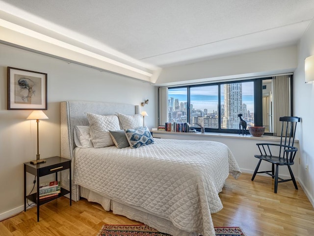 bedroom featuring a city view, baseboards, and wood finished floors