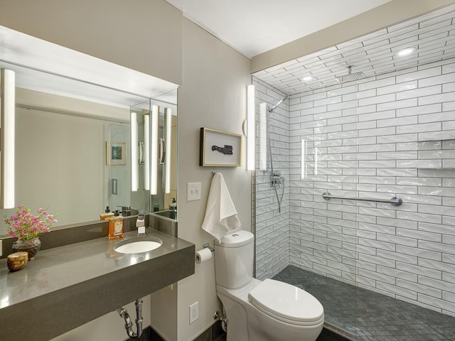 full bath with a sink, a tile shower, and toilet