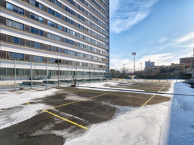 uncovered parking lot featuring a tennis court and fence