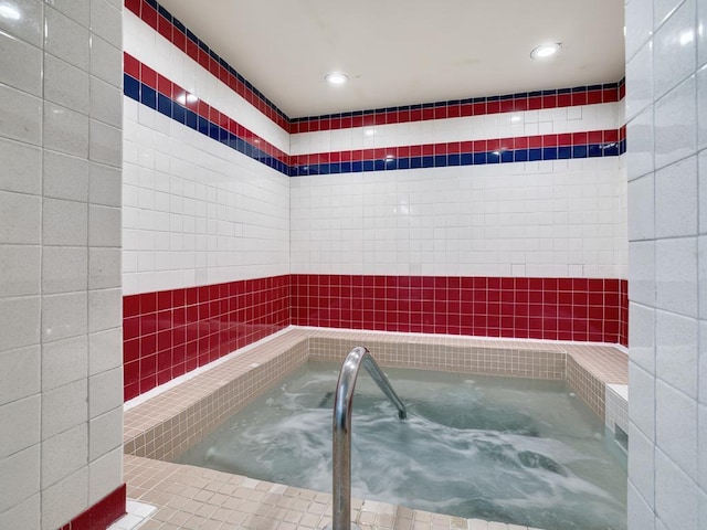 bathroom with a bathing tub, tile walls, and recessed lighting