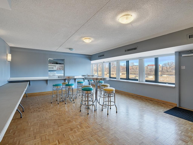 dining area with a textured ceiling, visible vents, and baseboards