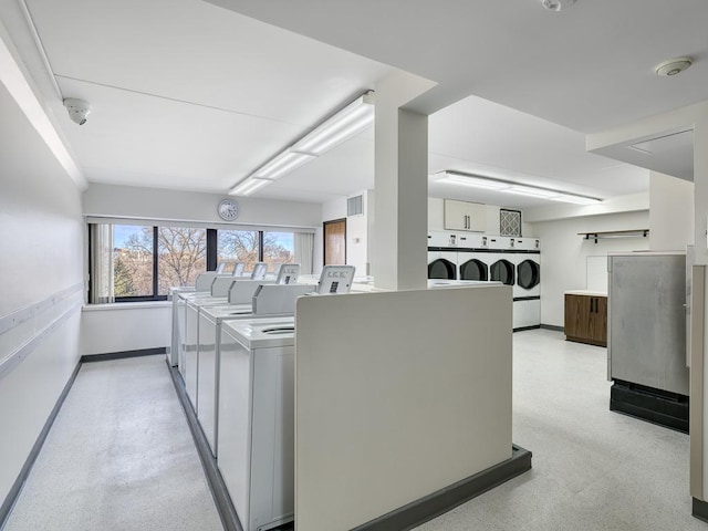 kitchen with baseboards, washer and clothes dryer, and light speckled floor