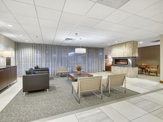 living area with light tile patterned floors, a paneled ceiling, recessed lighting, visible vents, and a large fireplace