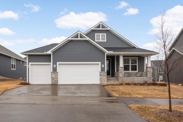 craftsman-style home featuring a porch, stone siding, driveway, and a garage