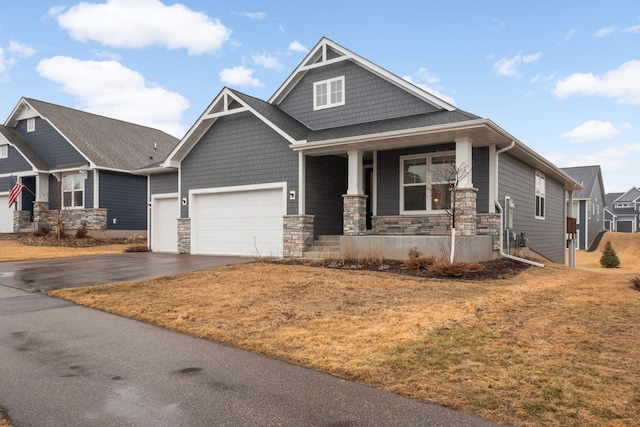 craftsman inspired home with driveway, stone siding, an attached garage, and a porch