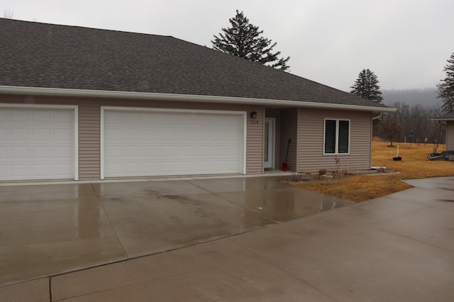 view of front of house with an attached garage, driveway, and a shingled roof