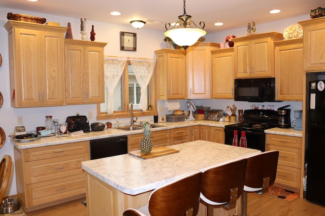 kitchen featuring black appliances, light brown cabinets, light countertops, and a sink