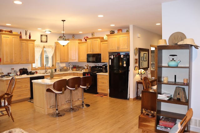 kitchen with black appliances, light brown cabinetry, a kitchen island, light wood finished floors, and light countertops