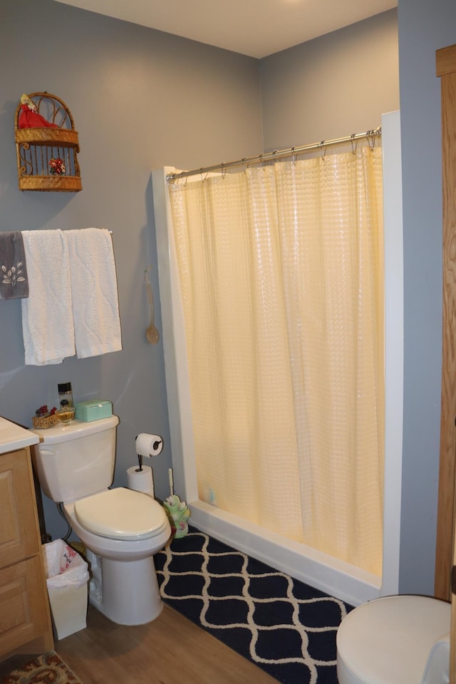 bathroom with curtained shower, toilet, and wood finished floors