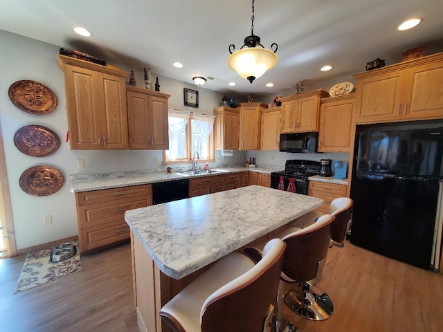 218 Thomas Dr, Rollingstone, MN 55969 - kitchen featuring black appliances, a sink, light wood finished floors, a center island, and a breakfast bar