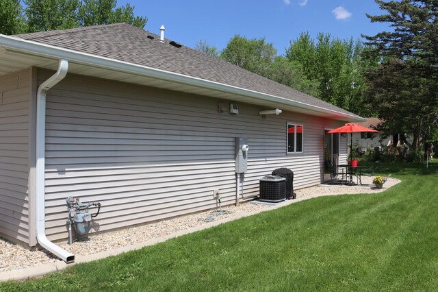 218 Thomas Dr, Rollingstone, MN 55969 - view of home's exterior featuring roof with shingles, a yard, central AC unit, and a patio area