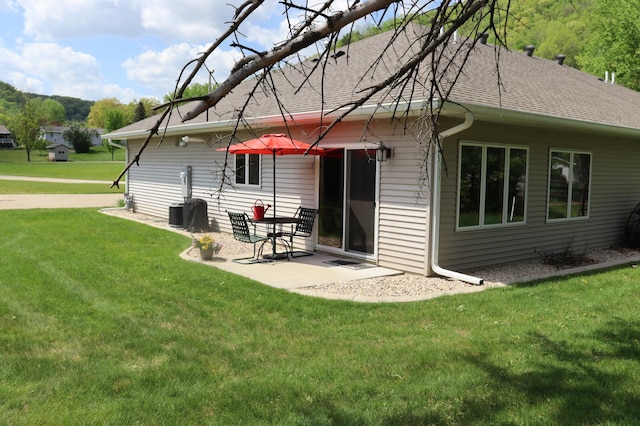 218 Thomas Dr, Rollingstone, MN 55969 - rear view of property featuring a lawn, a shingled roof, and a patio