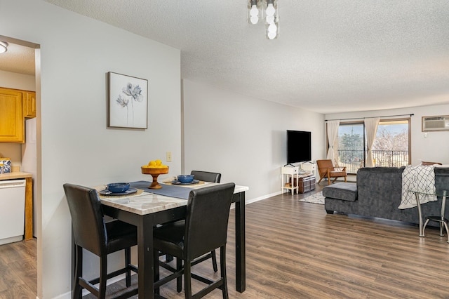 dining area with a textured ceiling, wood finished floors, baseboards, and a wall mounted AC