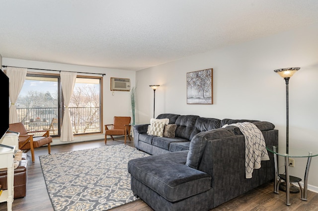 living room featuring a wall unit AC, wood finished floors, and a textured ceiling