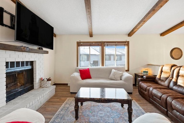 living area with a fireplace, a textured ceiling, wood finished floors, beamed ceiling, and baseboards