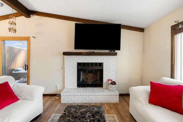 living room featuring lofted ceiling with beams, a fireplace, wood finished floors, and baseboards