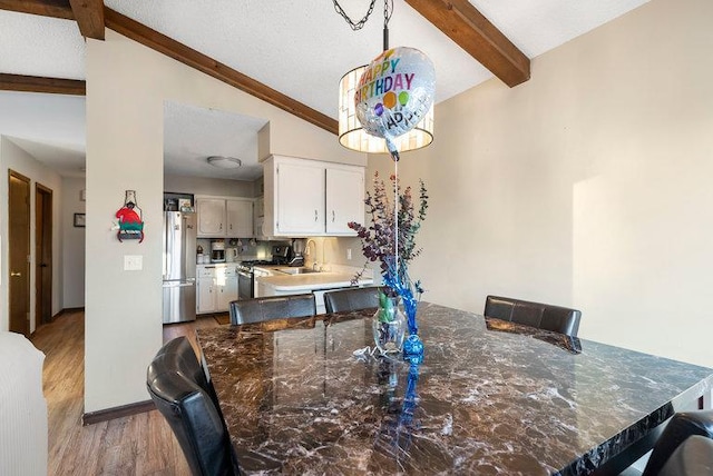 dining area with baseboards, lofted ceiling with beams, and light wood finished floors