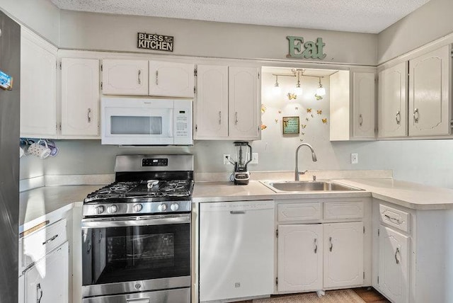 kitchen with dishwasher, white microwave, light countertops, stainless steel range with gas cooktop, and a sink