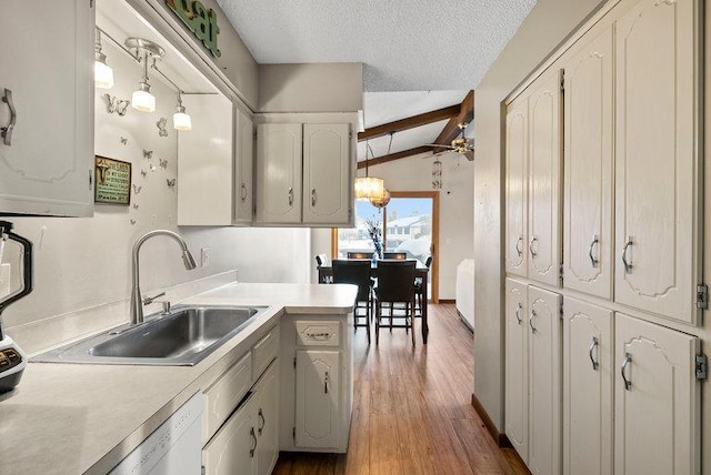 kitchen featuring wood finished floors, vaulted ceiling with beams, light countertops, a textured ceiling, and a sink