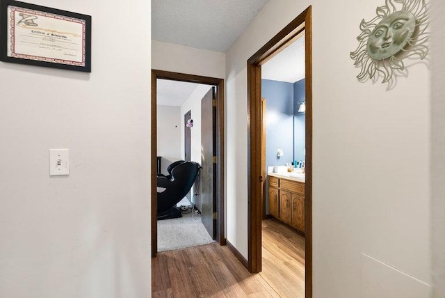 hallway featuring light wood finished floors and a textured ceiling