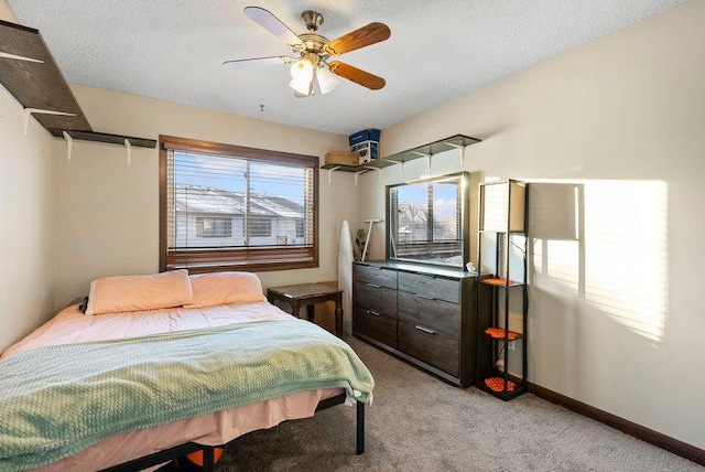 bedroom with a ceiling fan, light carpet, a textured ceiling, and baseboards