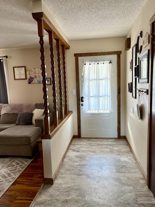 foyer with a textured ceiling, light wood-style floors, and baseboards