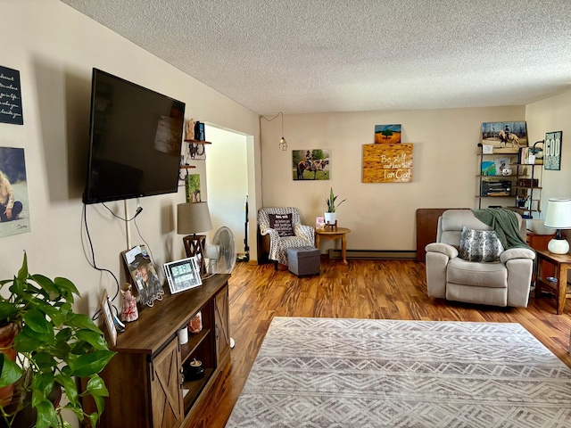 living room featuring a textured ceiling, a baseboard heating unit, and wood finished floors