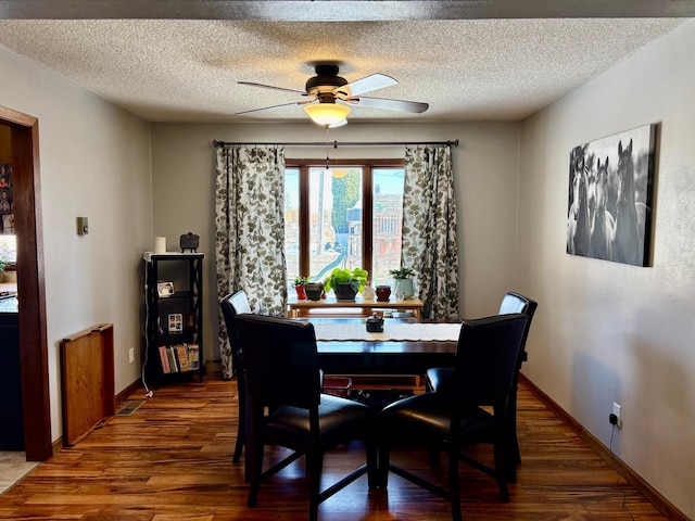 dining room with ceiling fan, a textured ceiling, baseboards, and wood finished floors